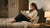 Lectrice installée dans un lit avec un coussin de lecture triangulaire, dans une ambiance douce et apaisante