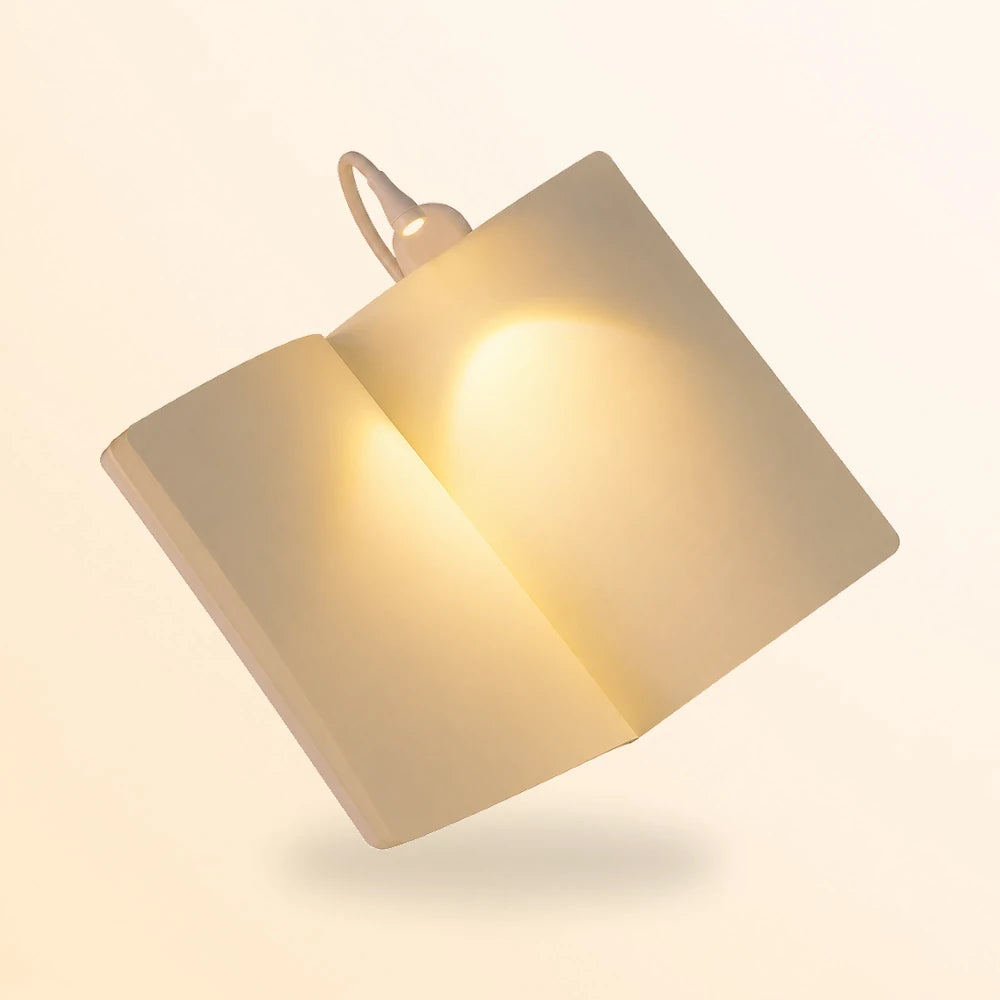 Lampe blanche mini clip light éclairant un livre tenu à deux mains dans la pénombre