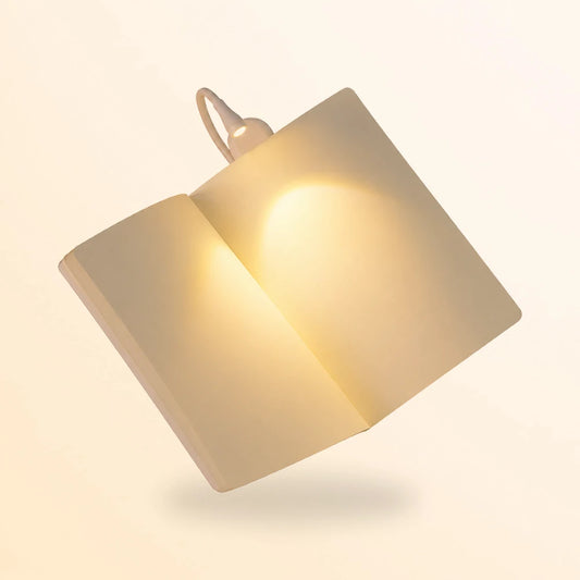 Lampe blanche mini clip light éclairant un livre tenu à deux mains dans la pénombre