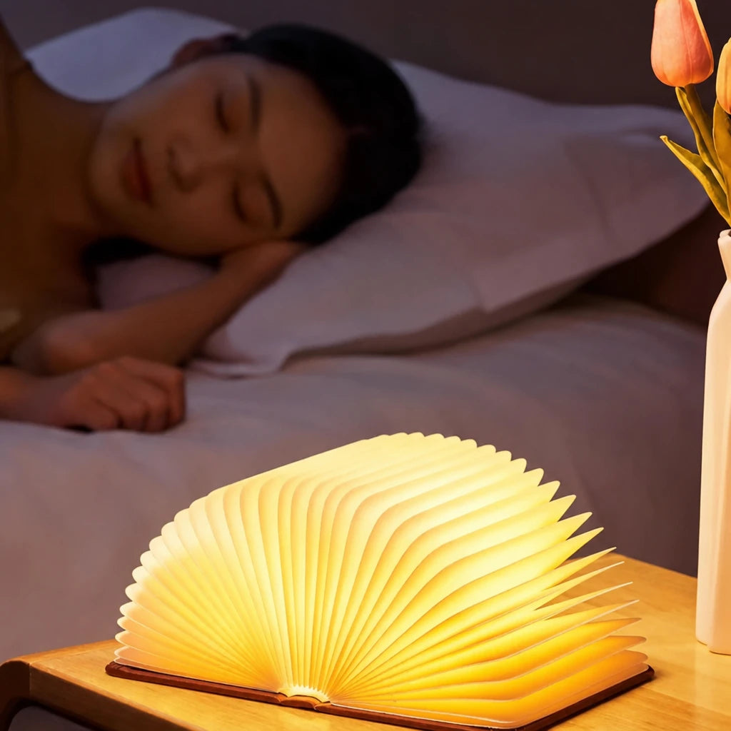 Lampe livre allumée sur une table de nuit, personne endormie à côté