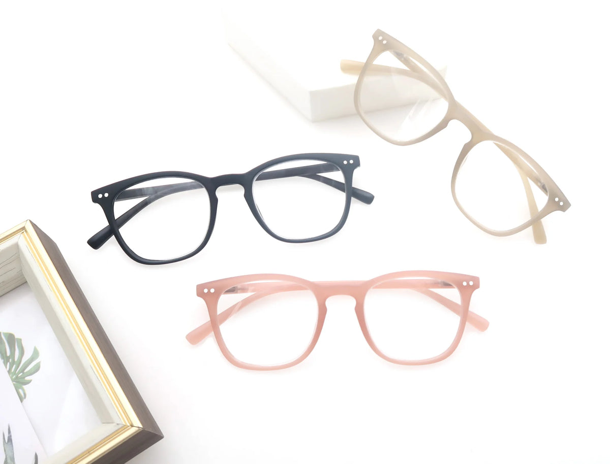Montures noire, beige et rose disposées près d'un cadre décoratif