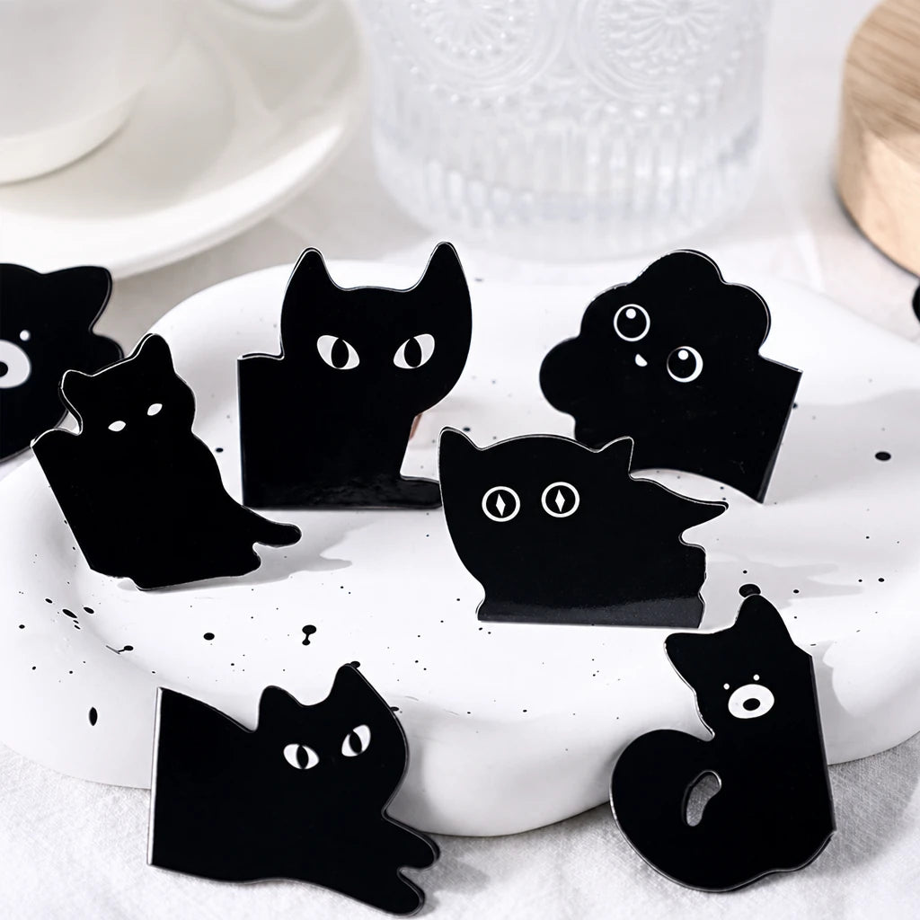 Gros plan sur plusieurs marque-pages magnétiques noirs en forme d'animaux posés sur un plat blanc