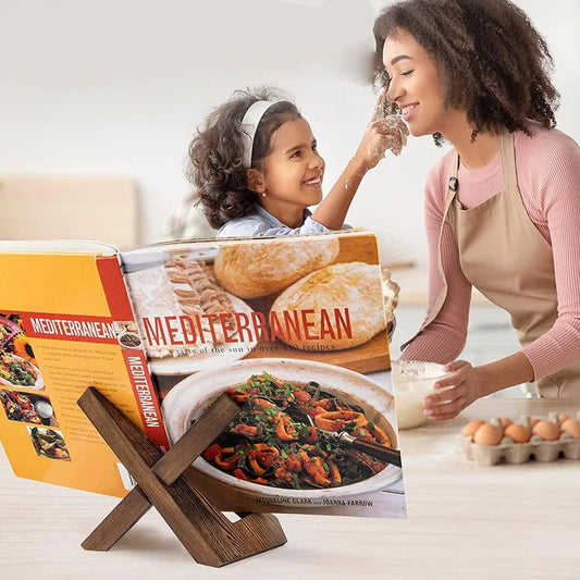 Livre de cuisine ouvert sur le support en bois devant une scène de pâtisserie
