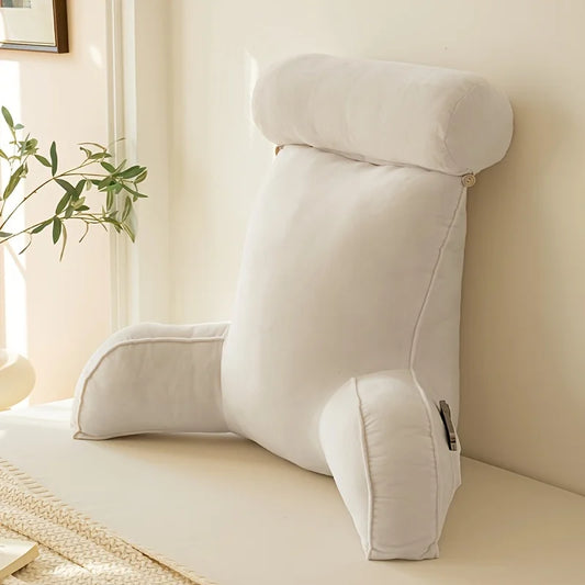 coussin de lecture blanc posé contre un mur, près d’une plante verte