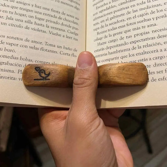 Main tenant un livre ouvert avec un petit support en bois placé sous le pouce