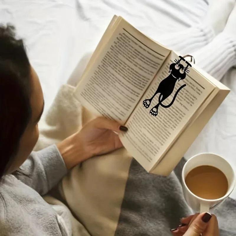 Personne lisant au lit avec le chat noir placé entre les pages