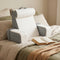 coussin de lecture blanc et gris posé sur un lit avec un livre ouvert