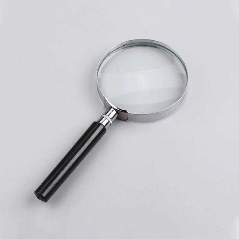 Loupe ronde avec cadre argenté et poignée noire sur fond clair