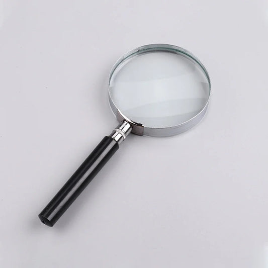 Loupe ronde avec cadre argenté et poignée noire sur fond clair