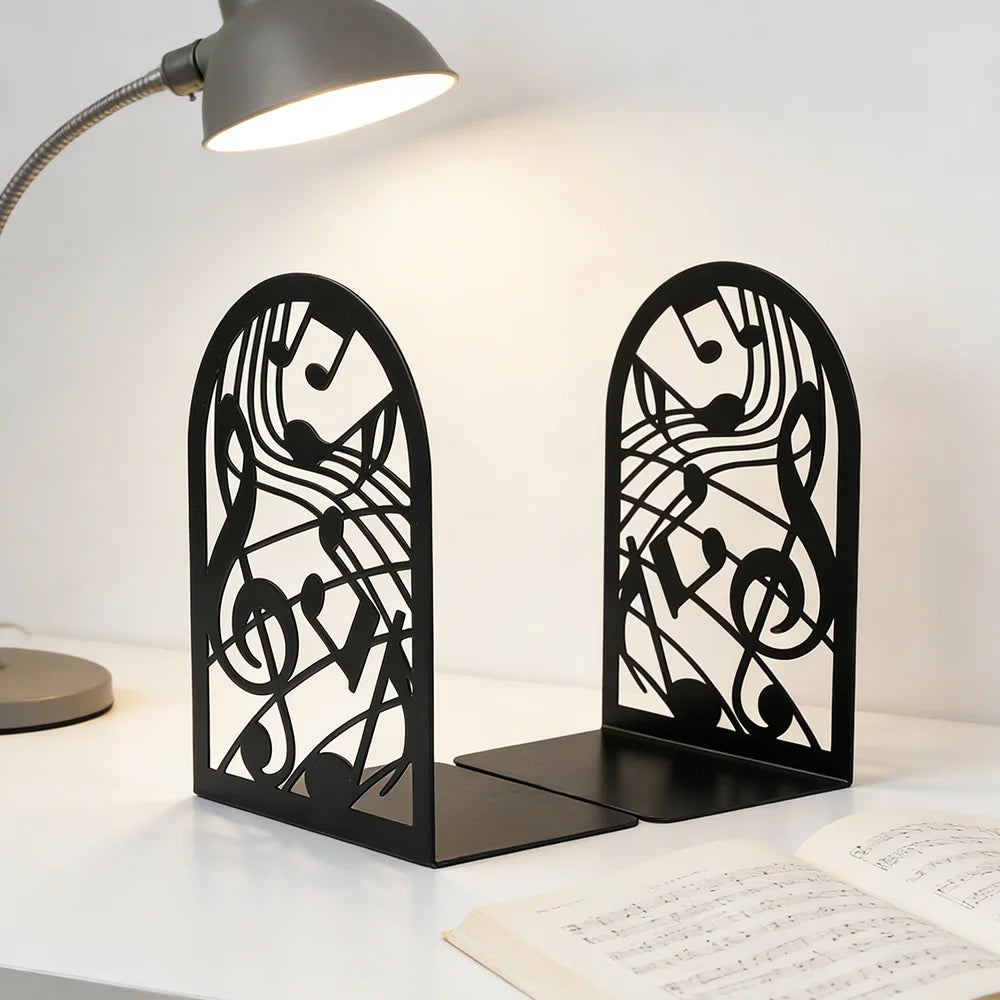 Paire de serre-livres note de musique en métal noir posés sur un bureau éclairé par une lampe