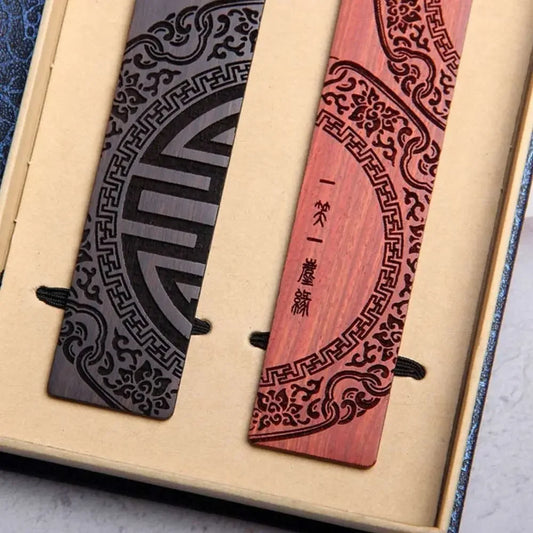 Vue de dessus de deux marque-pages en bois dans leur écrin doré, motifs circulaires gravés