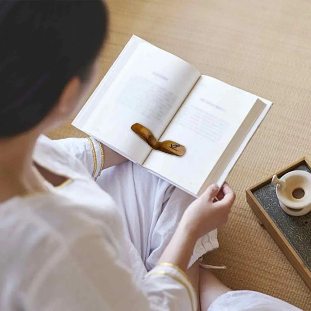 Personne lisant un livre ouvert maintenu par un support en bois