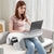 femme assise sur un canapé utilisant un coussin de lecture pour poser son ordinateur portable