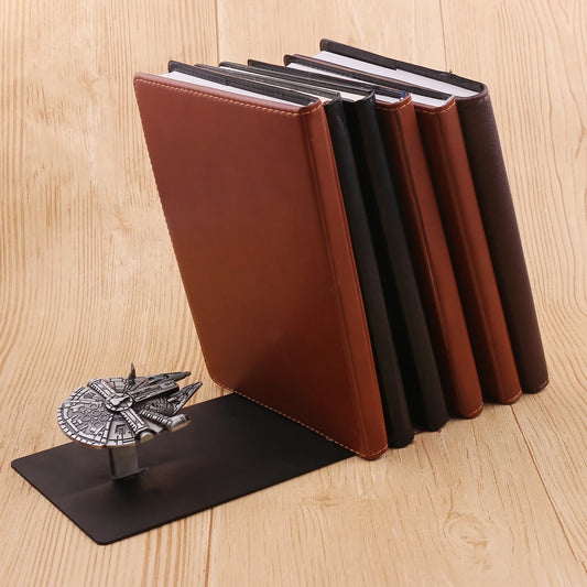 Support noir avec vaisseau argenté maintenant plusieurs livres sur une surface en bois