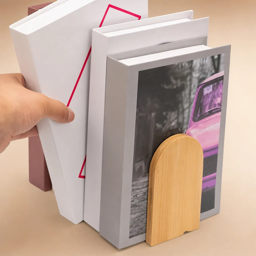 Main retirant un livre d'un groupe maintenu par un serre-livres en bois bambou en forme d'arche