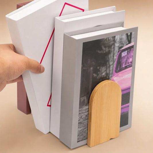 Main retirant un livre d'un groupe maintenu par un serre-livres en bois bambou en forme d'arche
