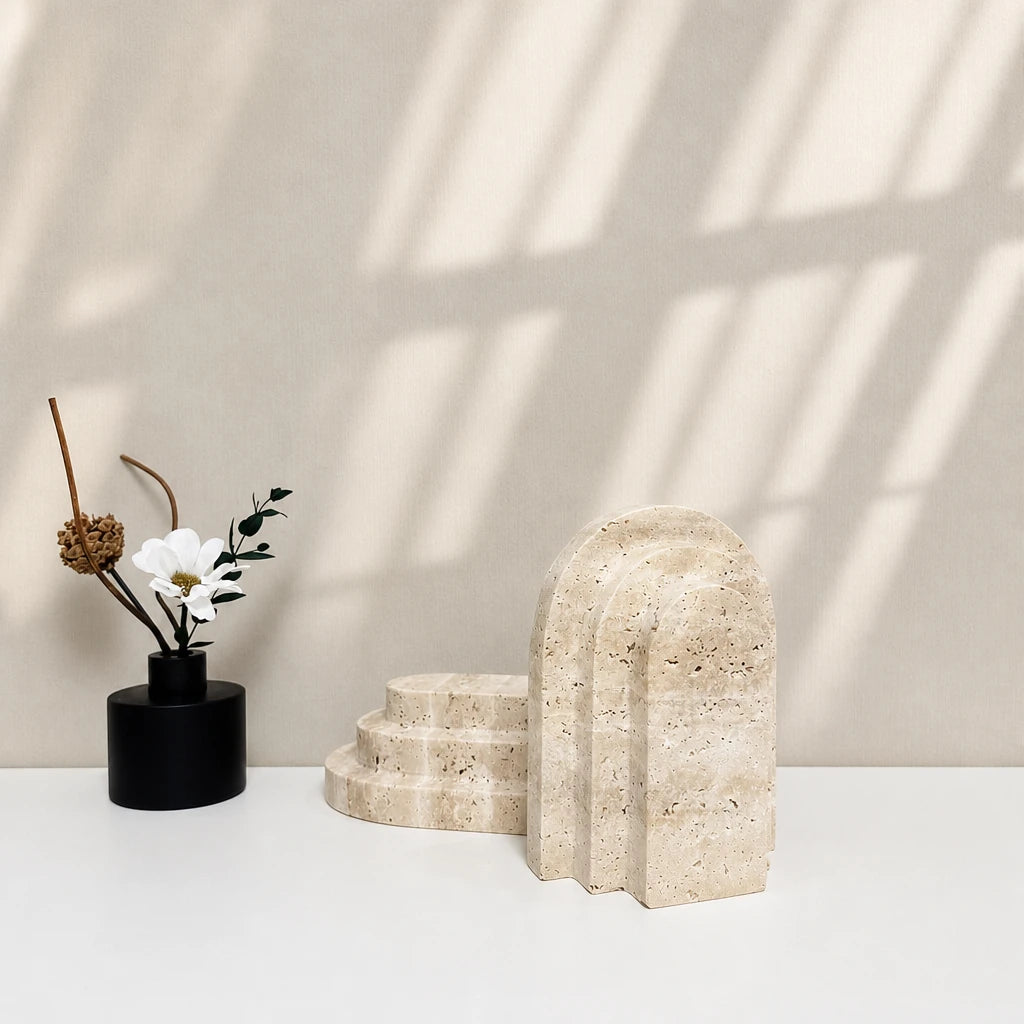 Deux modèles de serre-livres en marbre sur surface blanche : forme arche et forme escalier, avec décoration florale