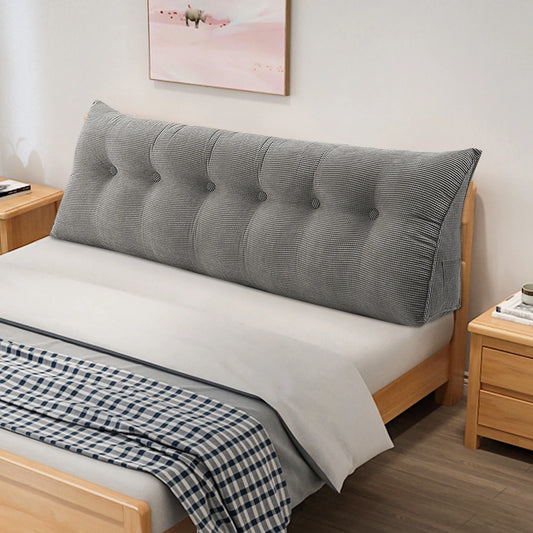 long coussin gris capitonné posé contre la tête de lit d’un lit en bois